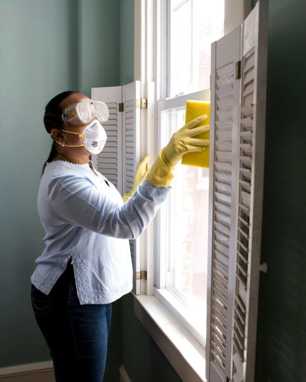 woman in white long sleeve shirt and blue denim jeans standing beside white wooden framed glass